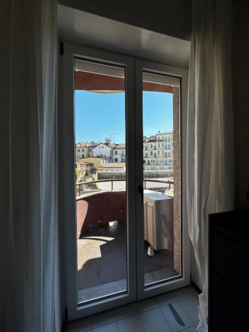 Vista attraverso porte in vetro sul balcone di Milano con panorama cittadino dell'Apartments Muratori