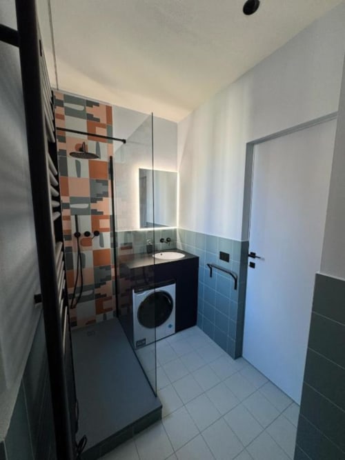 Bagno moderno negli Apartamenti Muratori Milano con doccia walk-in, lavatrice e parete decorata con piastrelle colorate