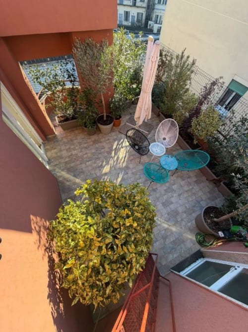 Terrazza degli Apartments Muratori Milano con posti a sedere, piante e ombrellone