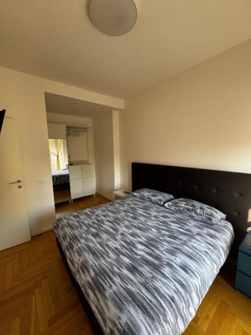 Camera da letto moderna nell'appartamento a Milano presso Muratori Apartments con letto, testata scura, parquet e bagno en-suite
