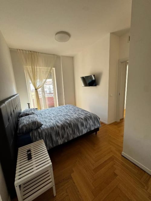 Camera moderna a Muratori Apartments Milano con letto matrimoniale, TV a parete, accesso alla terrazza e pavimento in spina di pesce