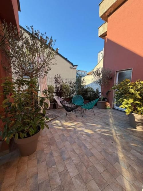 Terrazza moderna dell'Aparthotel Muratori Milano con sedie colorate, piante in vaso e zona living pavimentata