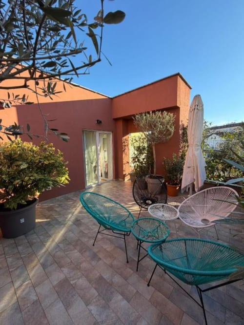 Terrazza moderna dell'appartamento a Milano con sedute colorate, piante in vaso e vista sul cielo sereno presso Muratori Apartments