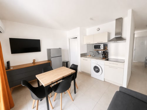 Cucina e sala da pranzo moderna presso la Residenza Marina di Bravone con armadi bianchi, elettrodomestici in acciaio inossidabile e legno