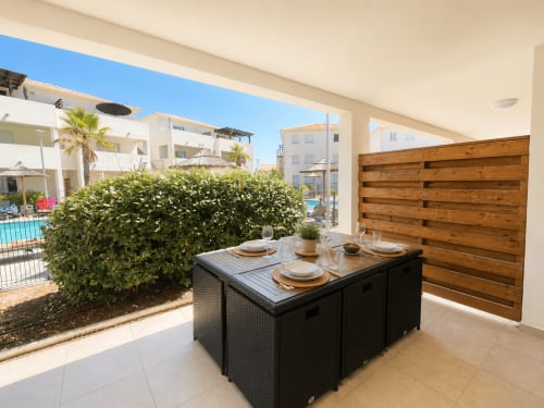 Terrasse moderne de Casa Di Bravone avec table à manger, vue sur piscine et paravent en bois donnant sur les appartements méditerranéens