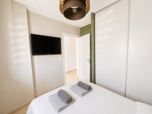Chambre moderne à Marina di Bravone avec literie blanche, télévision écran plat et décoration minimaliste