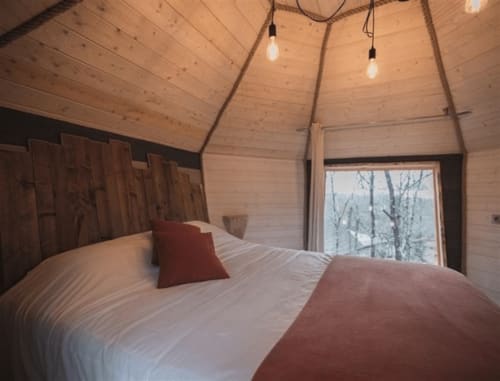 Chambre cosy en bois aux Murmures du Bois avec vue sur jardin, luminaires suspendus et décor rustique