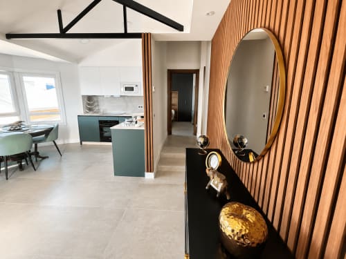 Entrada moderna del apartamento Holibai en Baiona con espejo redondo, paneles de madera, cocina y mobiliario contemporáneo