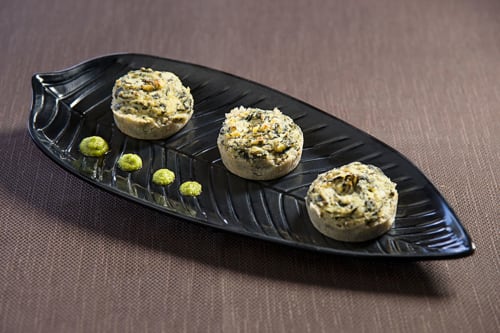 Tre funghi ripieni di erbe su un piatto nero a forma di foglia all'Hotel Ristorante alle Querce di Castelbuono