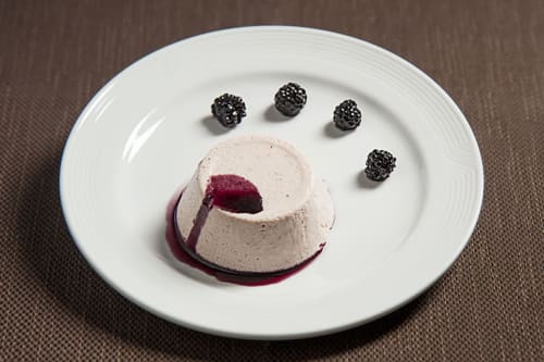 Elegante dessert in piatto con mousse di crema, coulis di frutti di bosco e more all'Hotel Ristorante alle Querce di Castelbuono