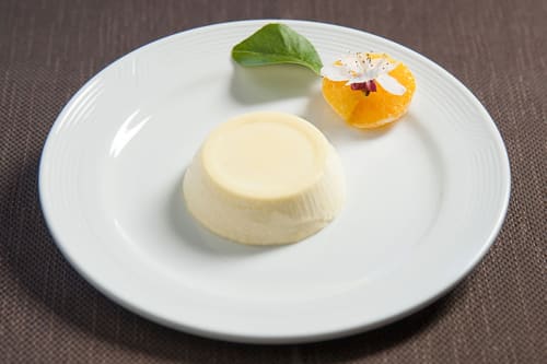 Elegante panna cotta con fetta d'arancia e fiore commestibile all'Hotel Ristorante alle Querce di Castelbuono