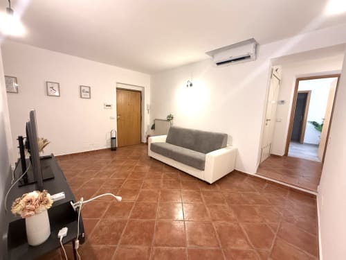 Ampio soggiorno negli Appartamenti Castelli ad Albano Laziale, con divano grigio, pavimenti in cotto e design moderno