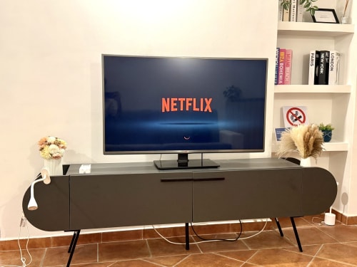 Soggiorno moderno presso Castelli Apartments con TV a schermo piatto su consolle scura, mensole bianche e accenti decorativi