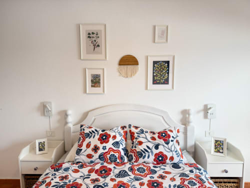 Acogedora habitación en apartamento Haller Homes Bajamar con cama blanca, ropa de cama floral colorida y arte botánico en las paredes