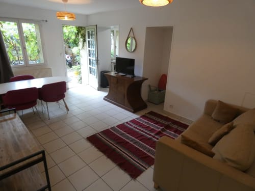 Appartement Sci Ludji à Nanterre avec vue sur jardin, canapé beige, coin repas, espace télé et décoration moderne