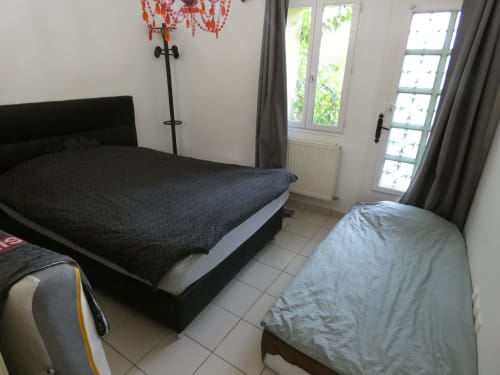 Chambre dans l'appartement Sci Ludji avec deux lits, portes donnant sur le jardin, mobilier moderne à Nanterre