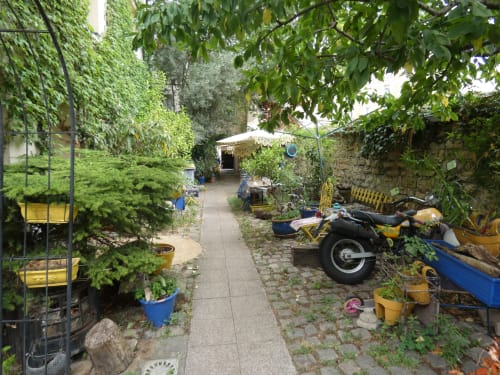 Cour verdoyante avec jardins à l'appartement Sci Ludji à Nanterre : plantes, mobilier de patio et terrasse ombragée