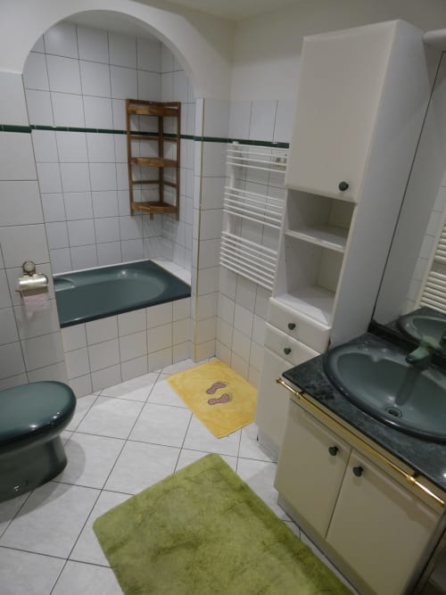 Salle de bain moderne de la villa Sci Ludji à Nanterre avec murs carrelés, fixtures vert foncé et rangements