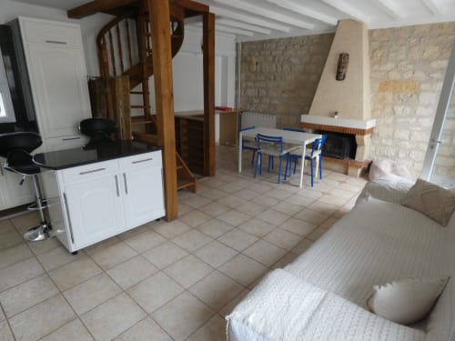 Espace de vie en villa ouverte avec escalier spiral, cuisine, table à manger avec chaises bleues, cheminée et canapé à Sci Ludji,
