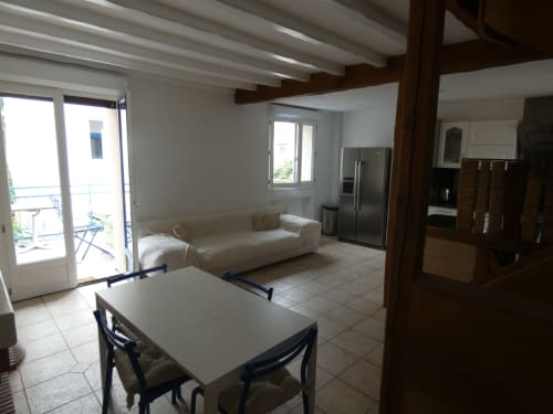 Lumineux espace de vie ouvert à la villa Sci Ludji avec table à manger, canapé beige, cuisine et accès terrasse à Nanterre