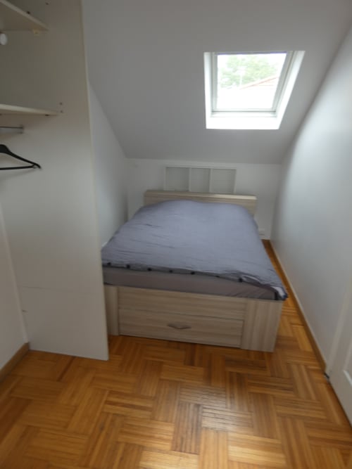 Chambre lumineuse sous les toits avec puits de lumière à la villa Sci Ludji à Nanterre, lit en bois et parquet