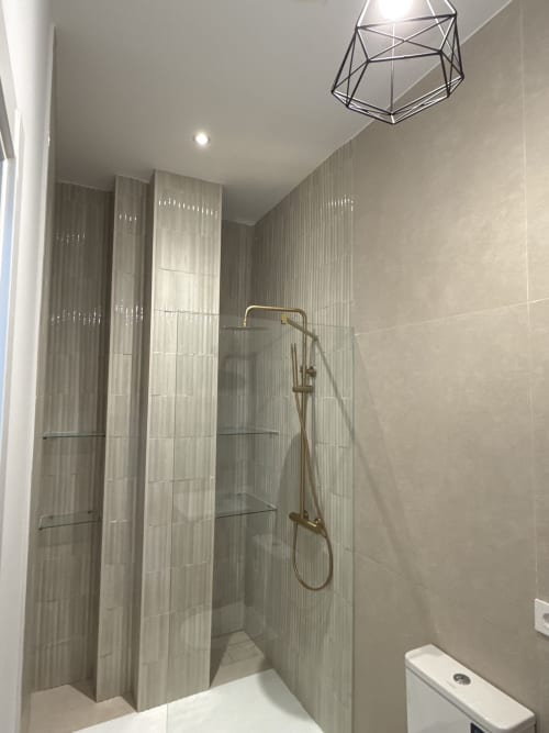 Modern bathroom with walk-in shower, vertical tile design, and geometric pendant light at Deiv Properties hotel in Cádiz,
