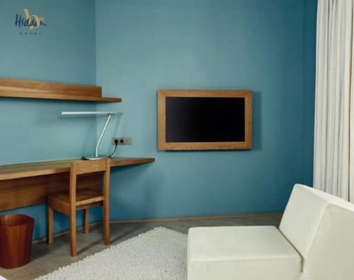 Chambre d'hôtel moderne au Hidden Bay Hotel avec murs turquoise, bureau en bois, sièges blancs et tableau noir encadré