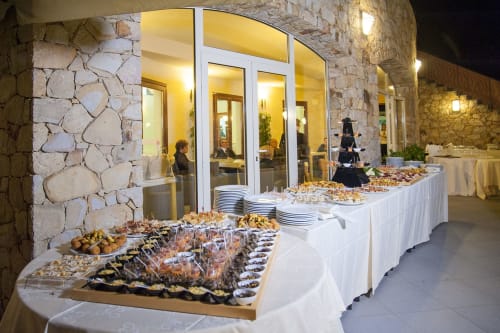 Elegante mise en place di buffet esterna all'Hotel Ristorante alle Querce di Castelbuono con antipasti e servizio di vini
