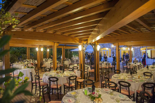 Elegante sala da pranzo dell'Hotel Ristorante alle Querce a Castelbuono con tavoli rotondi, sedie nere e travi in legno