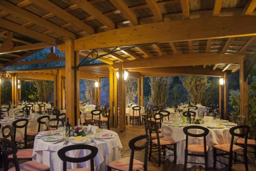 Elegante sala da pranzo dell'Hotel Ristorante alle Querce a Castelbuono con tavoli tondi, sedie nere e travi in legno