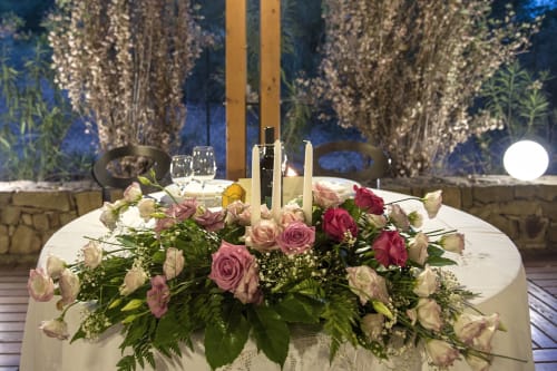 Tavolo da cena elegante all'Hotel Ristorante alle Querce di Castelbuono con composizione floreale e atmosfera illuminata da candele