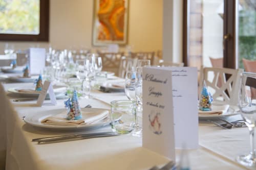 Elegante tavolo da pranzo all'Hotel Ristorante alle Querce di Castelbuono con mise en place, bicchieri e segnaposti decorativi