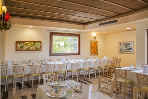 Elegante sala da pranzo dell'Hotel Ristorante alle Querce a Castelbuono con tavoli vestiti di bianco e sedie in legno