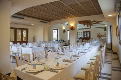 Elegante sala banchetti presso l'Hotel Ristorante alle Querce a Castelbuono con lunghi tavoli bianchi, coperto e legno