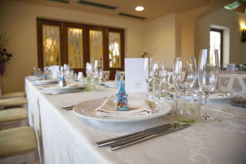 Elegante tavolo preparato all'Hotel Ristorante alle Querce di Castelbuono con tovaglie bianche, sottopiatti e bicchieri