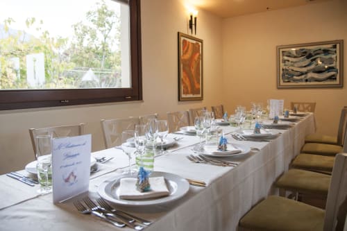 Elegante sala da pranzo dell'Hotel Ristorante alle Querce a Castelbuono con tavolo lungo formalmente preparato, coperto e giardino