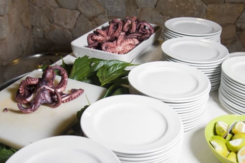 Fresco polpo e guarnizioni di lime esposti presso l'Hotel Ristorante alle Querce a Castelbuono con piatti bianchi impilati pronti per