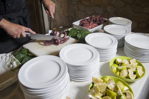 Chef prepara polpo all'Hotel Ristorante alle Querce di Castelbuono con limoni freschi e presentazione in piatto