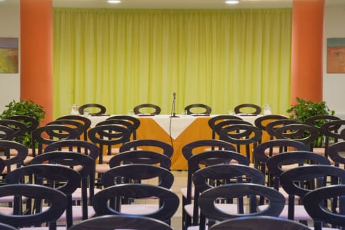 Sala conferenze moderna presso l'Hotel Ristorante alle Querce di Castelbuono con sedie nere e tende gialle