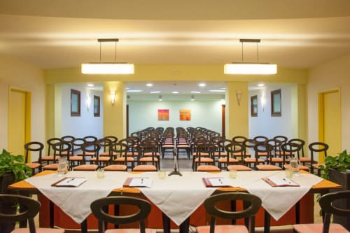 Sala conferenze Hotel Ristorante alle Querce con tavoli drappati di bianco, illuminazione moderna e posti a sedere per eventi