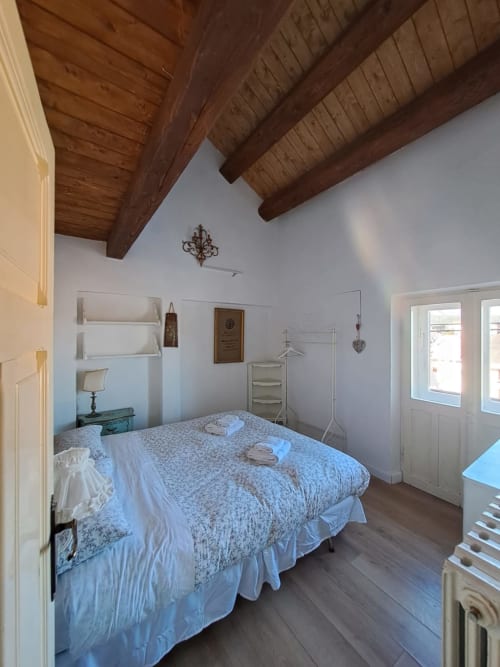 Camera da letto spaziosa nella villa Antico Chalet Momosa, Ovindoli, con travi in legno a vista, pareti bianche, letto matrimoniale con asciugamani, e