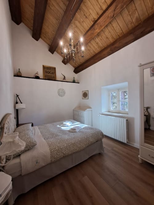 Camera da letto in villa Antico Chalet Momosa a Ovindoli con travi in legno a vista, lampadario, muri bianchi e vista montagna