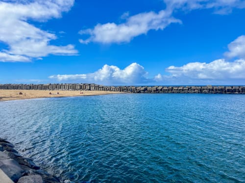 Oceano Atlântico azul-turquesa com praia de areia e quebra-mar protetor na villa SpecialStays em Funchal, Portugal