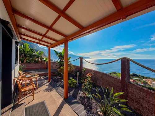 Terraço do oceano Atlântico na villa Casa do Pico em Funchal com pérgola de madeira, cadeiras de vime e vistas para o mar