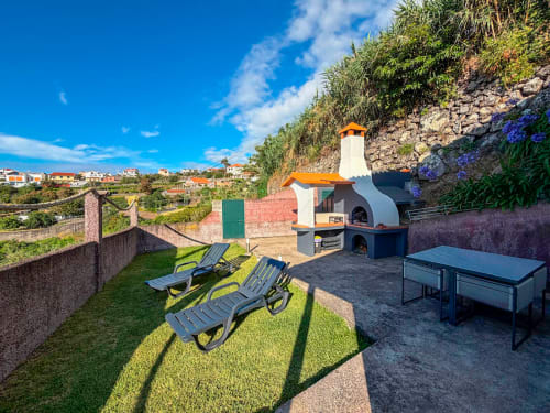 Pátio traseiro da vila Casa do Pico em Funchal com espreguiçadeiras, cozinha ao ar livre e vistas para o Oceano Atlântico