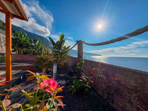 Jardim tropical com flores rosa com vista para o oceano Atlântico a partir do terraço da villa Casa do Pico em Funchal