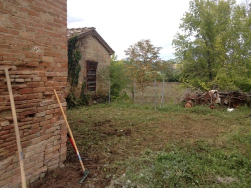 Rustic countryside property at Agriturismo La Frattina in Buonconvento, Siena with brick buildings and overgrown grounds