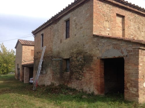 Rustic brick farmhouse with weathered terracotta walls at Agriturismo La Frattina in Buonconvento, Siena, Tuscany