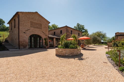 Tuscan countryside courtyard at Agriturismo La Frattina in Buonconvento, Siena, featuring brick buildings and orange