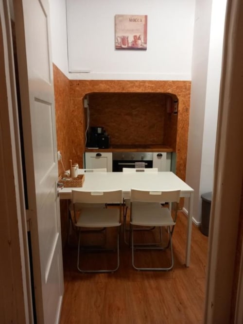 Compact dining area in Lisbon BnB apartment with small table, chairs, and kitchenette with appliances
